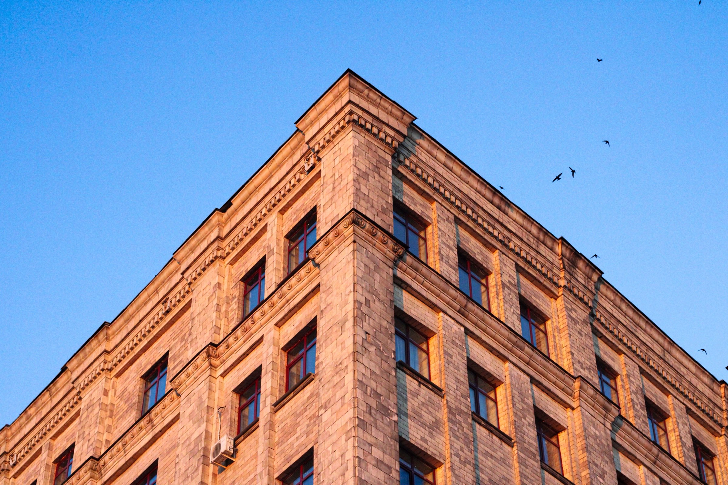 A warm-lit stone building against a clear blue sky